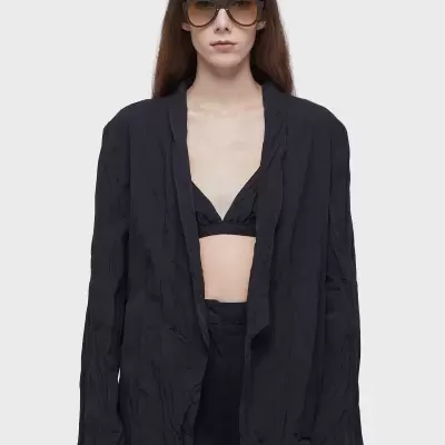 Mulher a usar blazer preto enrugado, top preto e óculos de sol grandes.