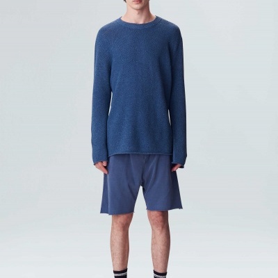 Homem com roupa casual azul e sapatilhas brancas.