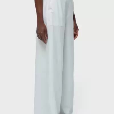 Calças largas brancas com cintura alta e bolsos, usadas com sandálias pretas