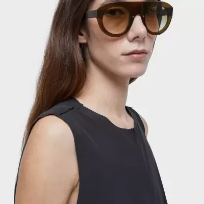 Óculos de sol grandes castanhos com lentes degradê castanhas em modelo com vestido preto