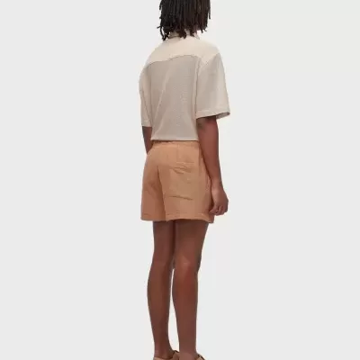 Pessoa de costas com camisa bege e calções castanhos claros e sapatos fechados