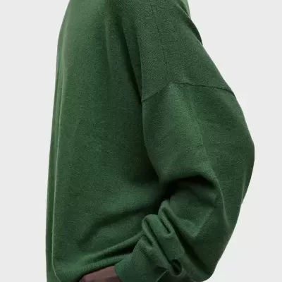 Camisola de malha verde com manga comprida em fundo cinza claro