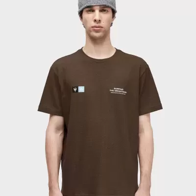 Homem com t-shirt castanha estampada e gorro cinzento