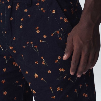 Calções pretos com padrão floral laranja e amarelo