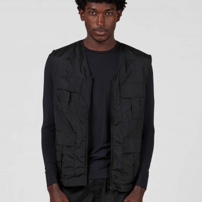 Colete preto com vários bolsos, usado por modelo contra fundo branco