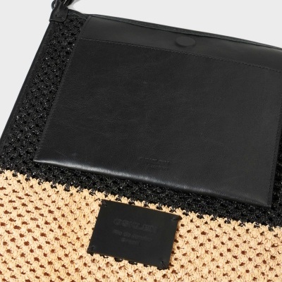 Mala preta e bege com textura trançada e couro liso, da marca Osklen