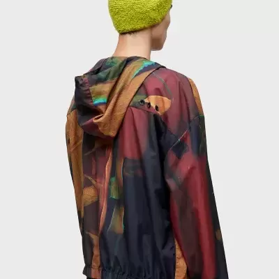 Casaco com padrão abstracto e capuz, usado por pessoa de costas com gorro verde claro