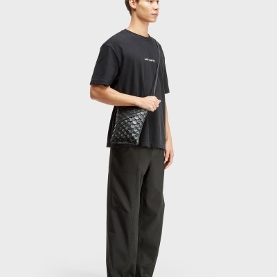 Homem com t-shirt preta e bolsa preta texturizada com alça transversal
