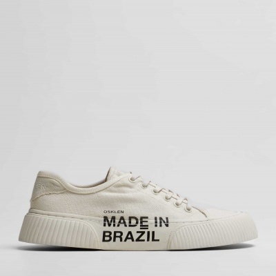 Ténis branco de lona com texto 'OSKLEN MADE IN BRAZIL' na lateral
