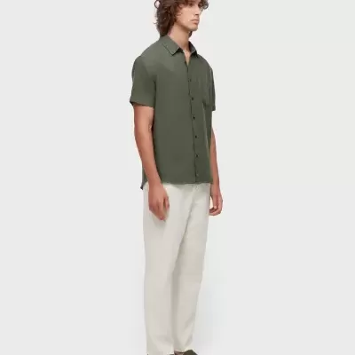 Homem com camisa verde, calças brancas e sapatos verdes