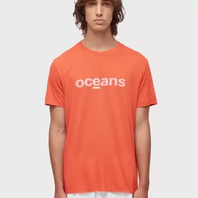 T-shirt casual laranja com texto branco 'oceans' e calças brancas