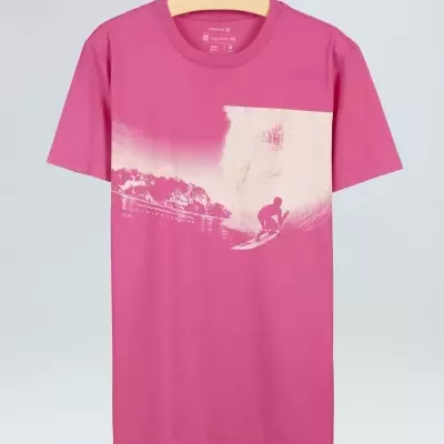 T-shirt rosa com estampa de surfista e mar pendurada num cabide.