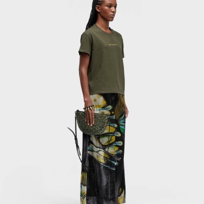 Mulher de vestido casual com t-shirt verde, saia estampada e mala verde