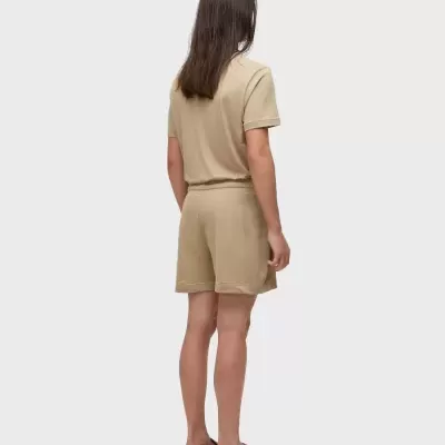 Pessoa de costas com conjunto bege de t-shirt e calções e calçado bege