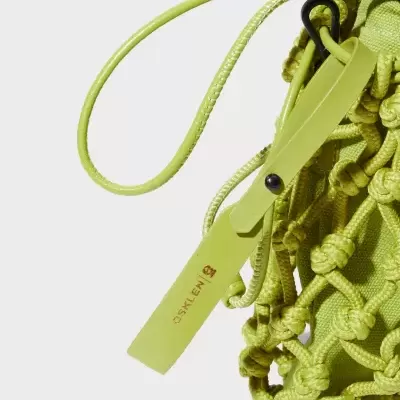 Bolsa verde lima com padrão de malha de nó em corda e alça em couro com etiqueta