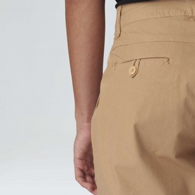 Calças bege com bolso traseiro e botão visível