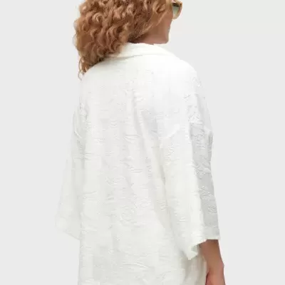 Casaco branco feminino com padrão floral texturizado visto de costas
