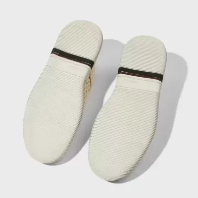 Sola branca de sapatos com textura riscada e faixa preta e vermelha no calcanhar