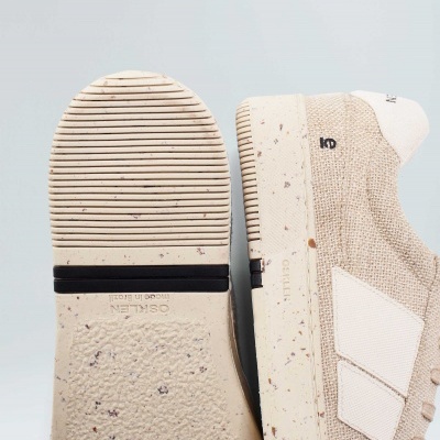 Sapatilhas bege com sola antiderrapante e detalhes brancos, texto visível na sola