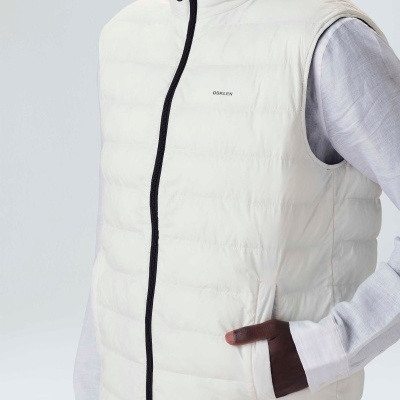 Colete acolchoado branco com fecho preto e logótipo no peito sobre camisa branca