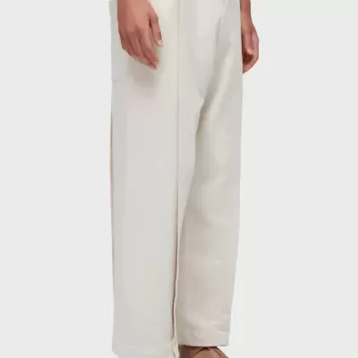 Calças largas brancas com cordão e sandálias castanhas em fundo branco