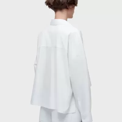 Pessoa de costas a usar camisa branca de tecido liso com gola clássica e punhos nas mangas