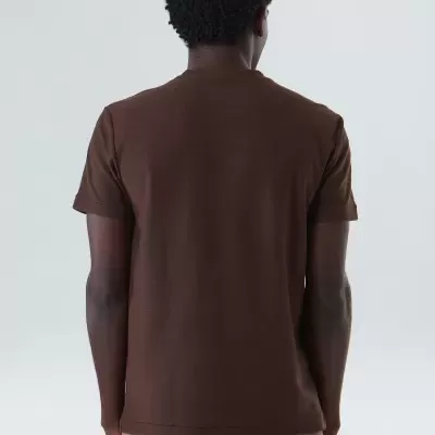 Homem de costas com t-shirt castanha e calças bege