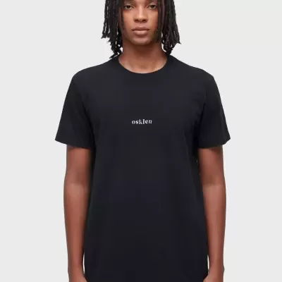 T-shirt preta com texto branco 'osnken' ao centro, usada por uma pessoa em fundo cinza claro