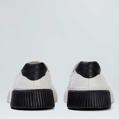 Sapatilhas brancas com sola preta e detalhe preto na parte traseira, vista de trás