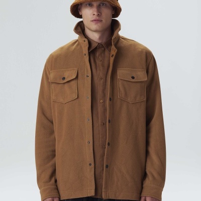 Homem com roupa castanha e calças de quadrados em fundo claro