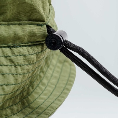 Chapéu bucket verde claro com cordão preto ajustável e botão com texto 'BASTIN'