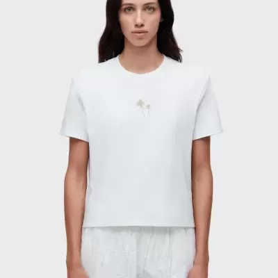 T-shirt branca com bordado de palmeiras douradas no peito.