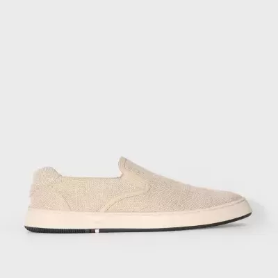 Tênis slip-on bege em tecido com sola branca e detalhe colorido na lateral.