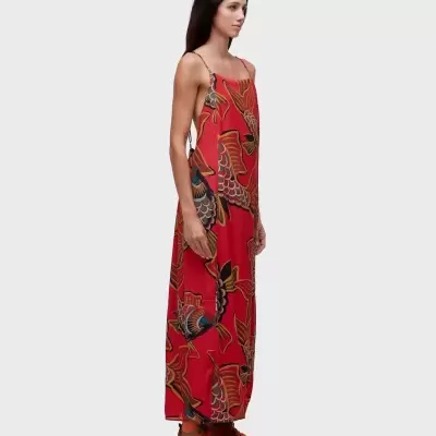 Vestido longo vermelho com padrão de peixes coloridos e sapatos castanhos.