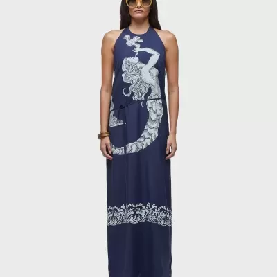 Vestido comprido azul escuro com estampa branca e óculos de sol amarelos em fundo branco.