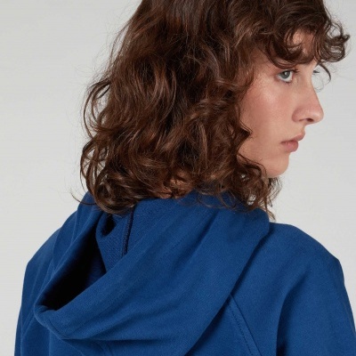 Casaco azul com capuz em pessoa vista de perfil com cabelo castanho ondulado