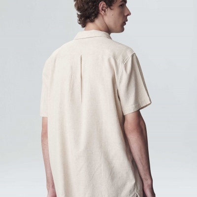 Homem de costas com camisa bege e calças cor-de-rosa com padrão