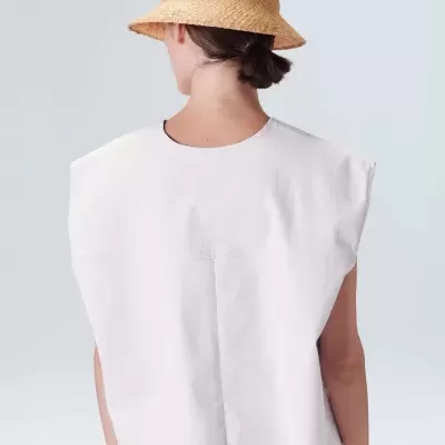 Mulher de costas com chapéu de palha e colete branco