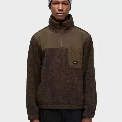 Homem com gorro cinzento e casaco castanho felpudo com bolso