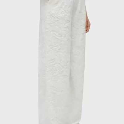 Calças largas brancas com padrão floral em relevo e bolsos frontais