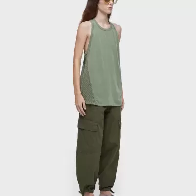 Mulher com camiseta verde claro, calças cargo verde escuro, sandálias pretas e óculos de sol amarelos