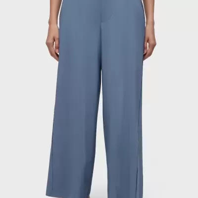 Calças longas azuis largas com cós alto e sapatos pretos com rede.