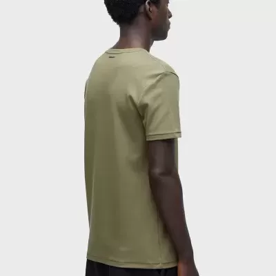 T-shirt verde-oliva masculina vista de costas com etiqueta no pescoço, usada com calças pretas