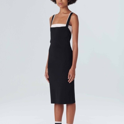 Vestido midi preto com alças largas e detalhe branco, meias brancas com riscas pretas e tênis brancos, fundo cinza claro.