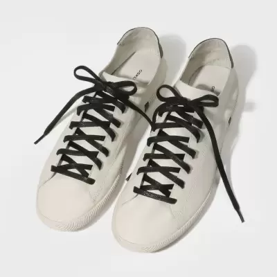 Par de sapatilhas brancas com atacadores pretos num fundo branco