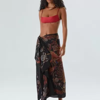 Mulher com top vermelho e saia preta com padrão floral