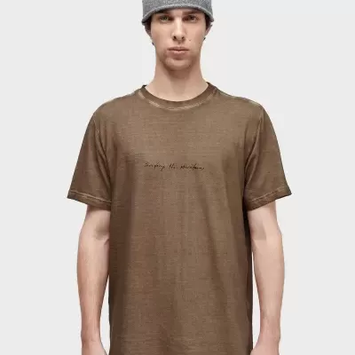 Homem com camisola castanha e gorro cinzento frente a fundo branco.