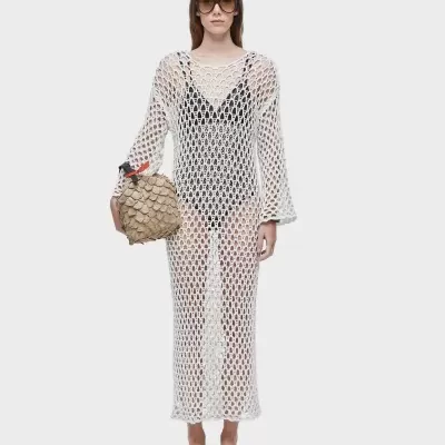 Vestido branco de malha comprido com padrão aberto em mulher com bolsa bege e óculos escuros