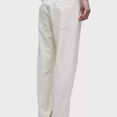 Calças brancas de tecido liso com bolso traseiro e cintura elástica usadas com ténis pretos e brancos