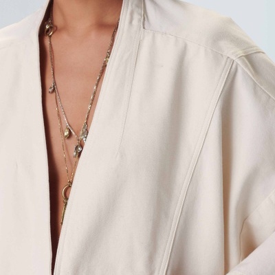 Roupa exterior branca com abertura frontal e corrente dourada com pendentes